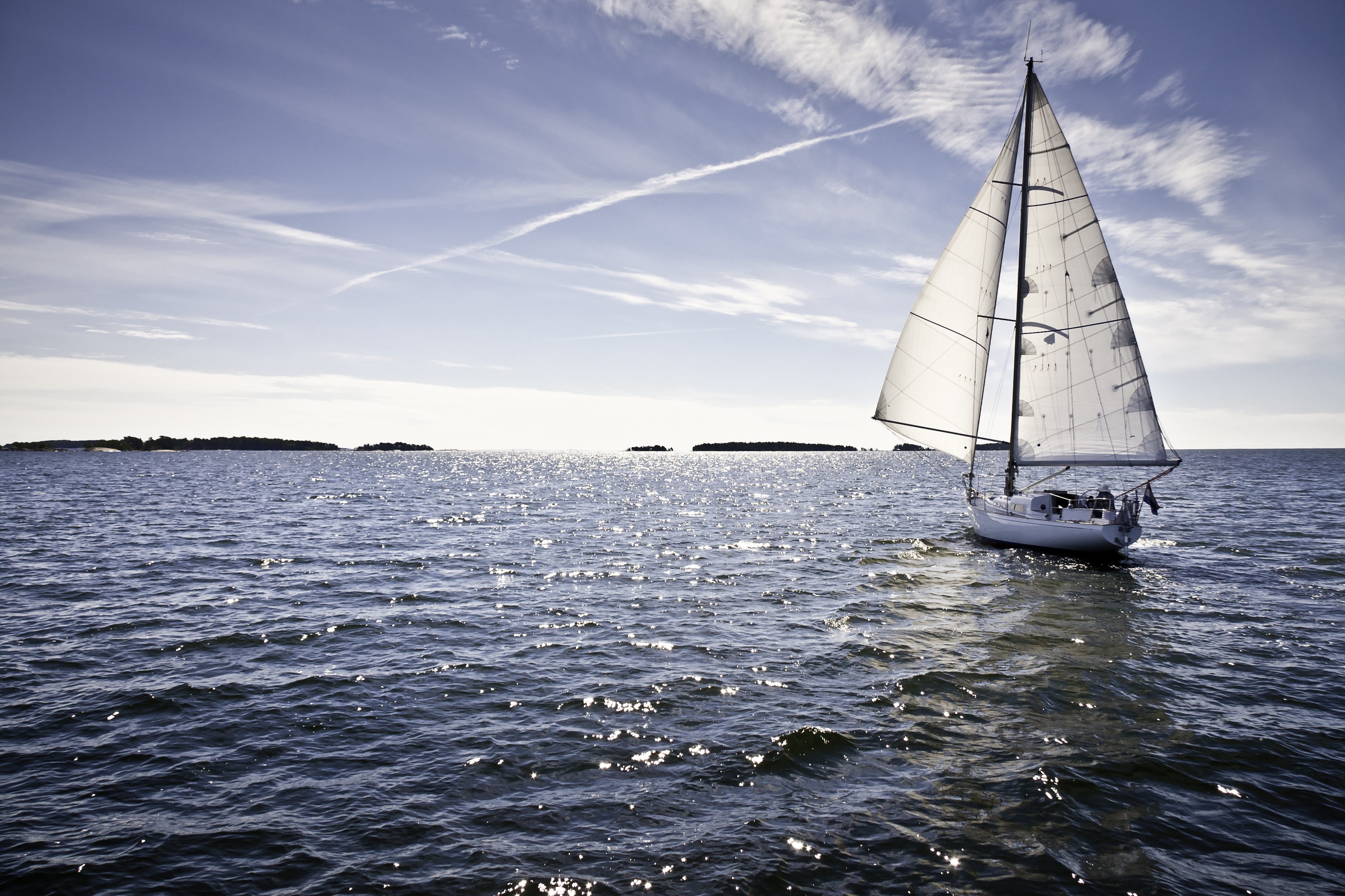Classic yacht sailing away against blue sky