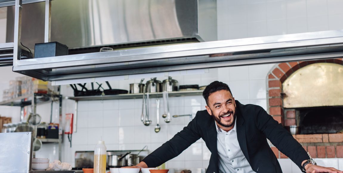 Smiling restaurant owner standing at kitchen counter